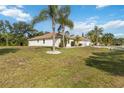 Well-maintained home featuring a lush lawn, mature palm trees, and an extended driveway leading to the garage at 5266 Wagon Wheel Dr, North Port, FL 34291