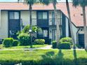 A close exterior view of a two-story home with balcony and lush landscaping on a pond at 5400 34Th W St # H12, Bradenton, FL 34210
