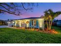 The light blue home has blue shutters, a manicured lawn and garden, complemented by a palm tree against a beautiful evening sky at 7817 Alhambra Dr, Bradenton, FL 34209