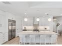 Bright white kitchen features a large island with seating, stainless steel appliances, and modern pendant lighting at 8069 Tidal Pointe Way, Sarasota, FL 34240
