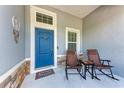 Cozy front porch featuring a blue door, charming decor, stone accents, and two comfortable chairs at 1219 Thornbury Dr, Parrish, FL 34219