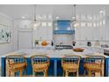 The luxury kitchen features a marble island, a blue range hood, and modern white cabinets at 135 Avenida Veneccia, Sarasota, FL 34242