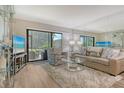 A bright living room with a large sliding door, comfortable seating, and a decorative glass shelving unit at 2055 Gulf Of Mexico Dr # G2-108, Longboat Key, FL 34228