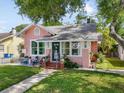 Charming pink home with a well-manicured lawn, white picket fence and inviting front porch seating area at 2330 7Th W Ave, Bradenton, FL 34205