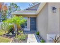 Close-up of the home's front door with decorative landscaping including palm trees and flower beds at 3429 97Th E Ln, Palmetto, FL 34221