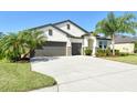 Charming home with a well-kept lawn, three-car garage, and lush landscaping, all under a bright blue sky at 364 Grande Vista Blvd, Bradenton, FL 34212