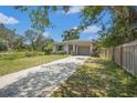 Single-story home with a manicured lawn, fenced yard, and a concrete driveway leading to a one car garage at 4251 Austin St, Sarasota, FL 34233