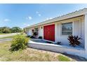 Close-up of front entrance showing red door, white trim, and tidy landscaping detail at 4535 Maceachen Blvd, Sarasota, FL 34233