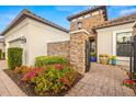 Elegant entryway featuring a stone accent wall, brick walkway, and colorful flower beds at 5011 Tivoli Run, Bradenton, FL 34211
