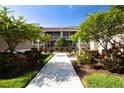 Condo exterior featuring a walkway, balcony, and lush landscaping on a sunny day at 5330 Hyland Hills Ave # 2324, Sarasota, FL 34241