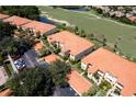 Aerial view of condos with tile roofs situated near golf course and lush green spaces, along with ample parking at 7155 Boca Grove Place Pl # 202, Lakewood Ranch, FL 34202