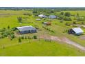 Scenic view of a gray home on a vast green property with multiple outbuildings at 7745 Wauchula Rd, Myakka City, FL 34251