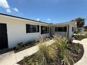 Front exterior featuring a clean stucco facade, decorative black shutters, and beautifully landscaped walkway at 808 25Th W Ave, Palmetto, FL 34221