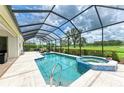 Screened-in pool with a spa and tiled patio, overlooking lush landscaping and a pristine golf course at 8206 Heritage Grand Pl, Bradenton, FL 34212