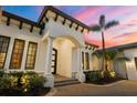 Close up of the home's entrance featuring an arched entryway, pillars, and a professionally landscaped yard at 8312 Catamaran Cir, Lakewood Ranch, FL 34202