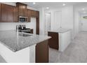 Kitchen featuring granite countertops, a stainless steel microwave and oven with stone-look tile flooring at 8632 Snowfall St, Sarasota, FL 34241