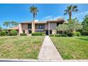 Inviting townhouse with manicured lawn, mature palm trees, and walkway to entrance at 935 Sunridge Way # B4, Sarasota, FL 34234