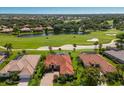An aerial view shows the property with a red tile roof near a golf course, a lake, and other homes at 9719 Discovery Ter, Bradenton, FL 34212