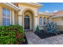 Arched doorway leads to a black front door, framed by lush landscaping and a brick paver walkway at 9719 Discovery Ter, Bradenton, FL 34212