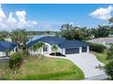 Beautiful view of a home next to the water with a well-manicured lawn and three car garage at 10055 Franklin Dr, Englewood, FL 34224