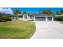 Well-maintained one-story home featuring a three-car garage and lush green lawn at 10055 Franklin Dr, Englewood, FL 34224