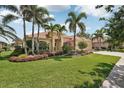 Beautiful home features a lush green lawn with vibrant, colorful flower beds at 1251 Tuscany Blvd, Venice, FL 34292