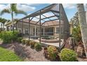 Exterior view of a screened-in pool with a brick jacuzzi and blooming flowers in a landscaped yard at 1251 Tuscany Blvd, Venice, FL 34292