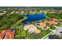Aerial view of a stucco home with a screened pool, terra cotta tile roof, and surrounded by a lake at 12520 Natureview Cir, Bradenton, FL 34212