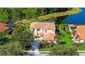 Aerial view of a yellow stucco house, terra cotta tile roof, solar panels, mature trees, and pond at 12520 Natureview Cir, Bradenton, FL 34212