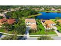 Aerial view of a yellow stucco home with terra cotta tile roof located on a pond, surrounded by mature landscaping at 12520 Natureview Cir, Bradenton, FL 34212