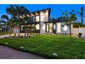 Elegant modern home with dark accents, manicured lawn, landscape lighting, and lush tropical landscaping at 1323 Loma Linda Ct, Sarasota, FL 34239