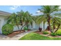Inviting front entrance with tropical landscaping, mature palm trees and a covered front porch at 1334 De Prie Rd, Englewood, FL 34223