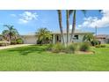Beautiful single-story home with lush green lawn, palm trees, and well-maintained landscaping at 1334 De Prie Rd, Englewood, FL 34223