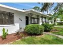 Inviting white home featuring dark trim, a covered entry, and fresh landscaping with green shrubs and plants at 326 25Th W St, Bradenton, FL 34205