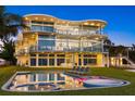 Beautiful view of the expansive modern house with large windows, a pool, and lounge chairs on a grassy lawn at 4035 Bay Shore Rd, Sarasota, FL 34234