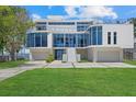 Modern waterfront home with sleek white exterior, glass windows, and an expansive driveway with manicured lawn at 4035 Bay Shore Rd, Sarasota, FL 34234