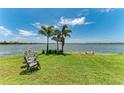 Lush backyard featuring a grassy lawn and a tranquil lake view with chairs and dock at 501 Maraviya Blvd, Nokomis, FL 34275