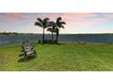 Tranquil backyard with lake views, mature trees, a grassy lawn, and outdoor seating at 501 Maraviya Blvd, Nokomis, FL 34275