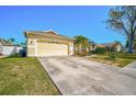 Exterior showcasing a spacious driveway leading to the attached garage, complemented by lush landscaping and a palm tree at 5565 Sweetwater Oak Dr, Sarasota, FL 34232