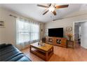 Bright living room featuring a TV, wood floors, ceiling fan, and large window with natural light at 712 68Th W Ave, Bradenton, FL 34207