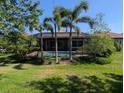 Landscaped backyard with lush lawn, pool, mature trees and plants, and outdoor living space at 119 Maraviya Blvd, Nokomis, FL 34275