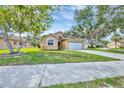Inviting single-story home featuring a lush green lawn, mature trees, and an attached two-car garage at 1451 Fawnwood Cir, Sarasota, FL 34232