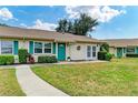 Inviting single-story home with a vibrant green front door, manicured landscaping, and a stone walkway at 1906 Canterbury Ln # 16, Sun City Center, FL 33573