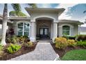 Elegant home entrance with a stone pathway, arched entryway, and well-maintained landscaping at 2149 Muskogee Trl, Nokomis, FL 34275