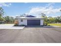 A well-lit, oversized garage showcasing its modern design and ample parking space, accented by neat landscaping at 2255 61St St, Sarasota, FL 34243