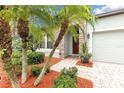 Inviting front entrance with a brick walkway, lush greenery, and a vibrant red front door at 2334 50Th Street E Cir, Palmetto, FL 34221