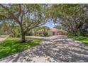 Long driveway leading to a single-story home surrounded by mature trees and well-manicured lawn at 2914 Dick Wilson Dr, Sarasota, FL 34240