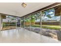 Screened-in patio featuring white tile flooring and views of the fenced backyard and mature trees at 4155 Center Gate Blvd, Sarasota, FL 34233
