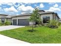 Charming home boasts a three-car garage, stone accents, tile roof, lush landscaping, and a brick paver driveway at 4971 Oyster Pearl St, Bradenton, FL 34211
