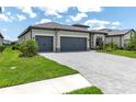 Charming home boasts a three-car garage, stone accents, tile roof, lush landscaping, and a brick paver driveway at 4971 Oyster Pearl St, Bradenton, FL 34211